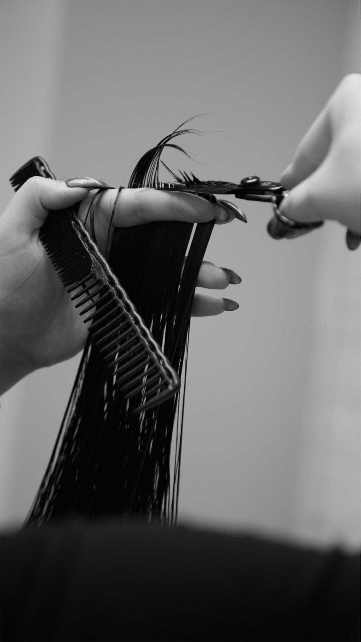 Hair being cut with scissors and comb in a salon setting.
