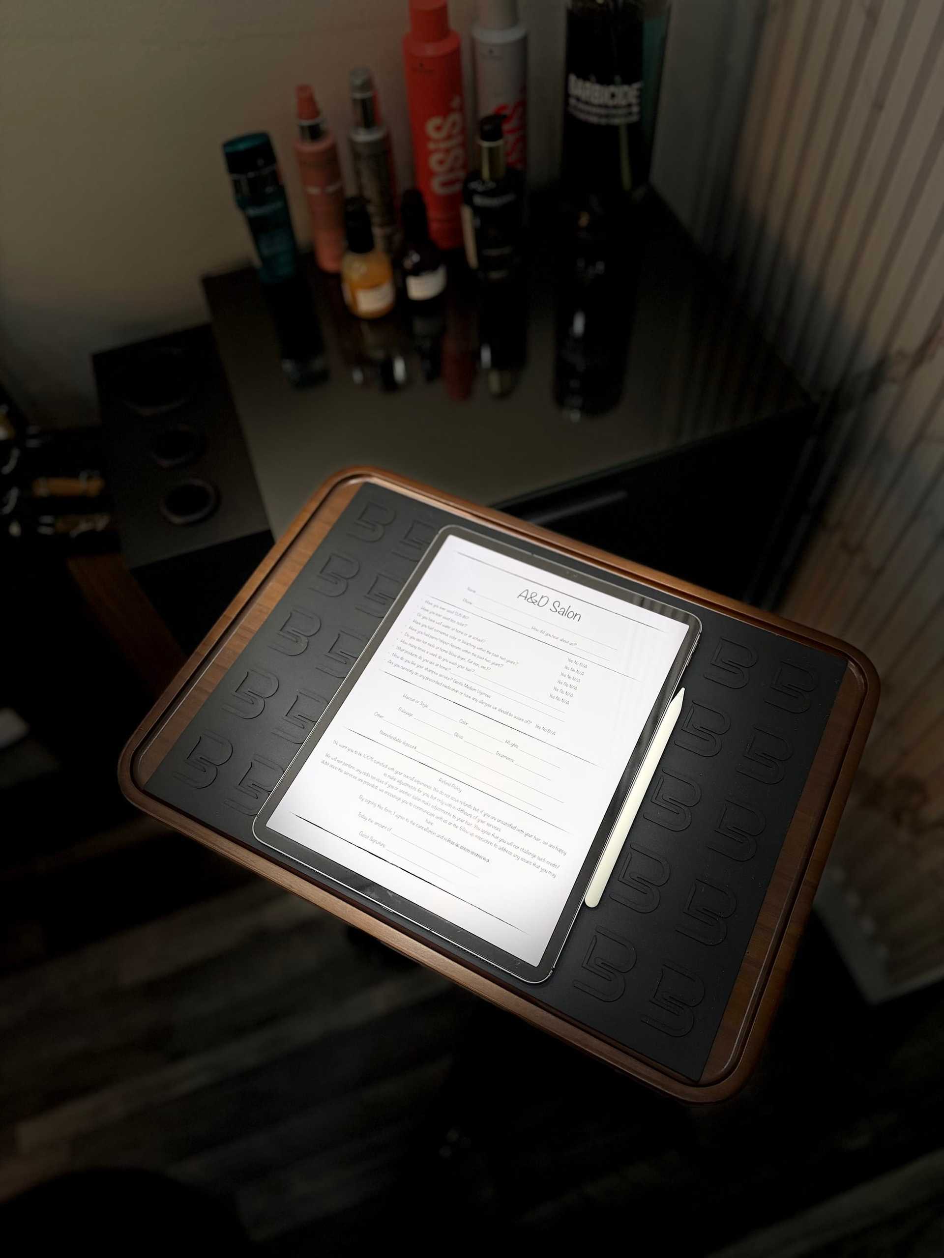 Tablet displaying a salon price list on a wooden tray in a modern styling station.