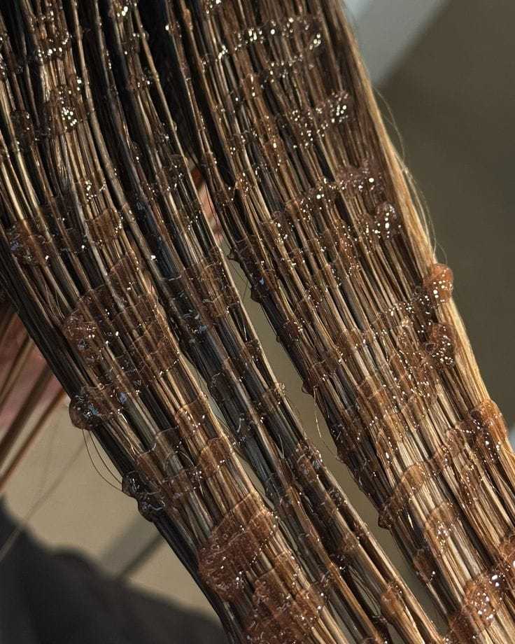 Hair being coated with brown dye, strands neatly separated for thorough application.