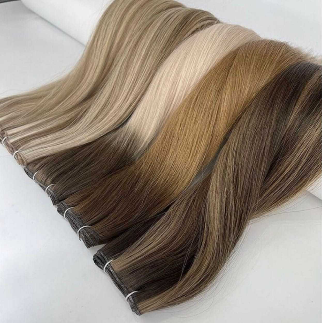 Various shades of hair extensions displayed on a white surface.